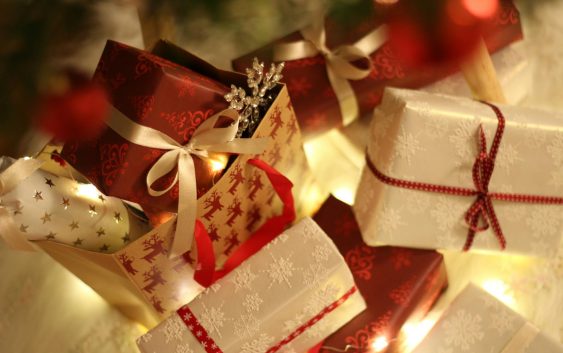 Beautifully wrapped Christmas presents under the tree with festive decorations and ribbons.